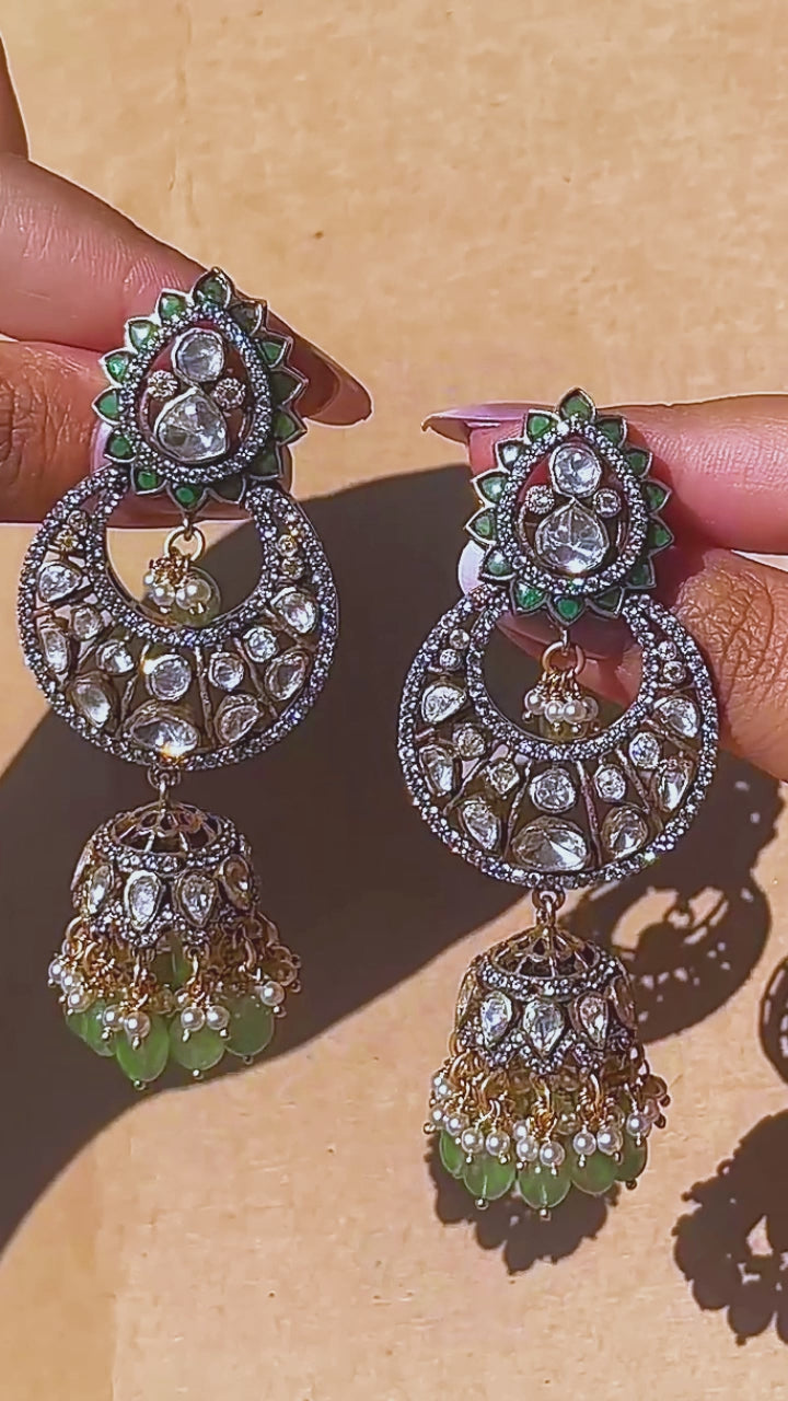 Gold-plated 925 silver crescent kundan jhumka earrings with lotus motifs, green gemstone beads, pearls, and zircon accents for festive and wedding wear