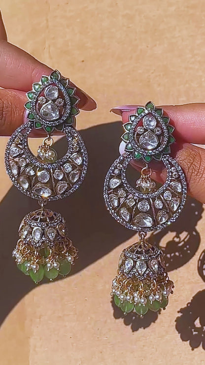 Gold-plated 925 silver crescent kundan jhumka earrings with lotus motifs, green gemstone beads, pearls, and zircon accents for festive and wedding wear